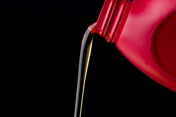 pouring heating oil from a red container depicting stability & quality during summer