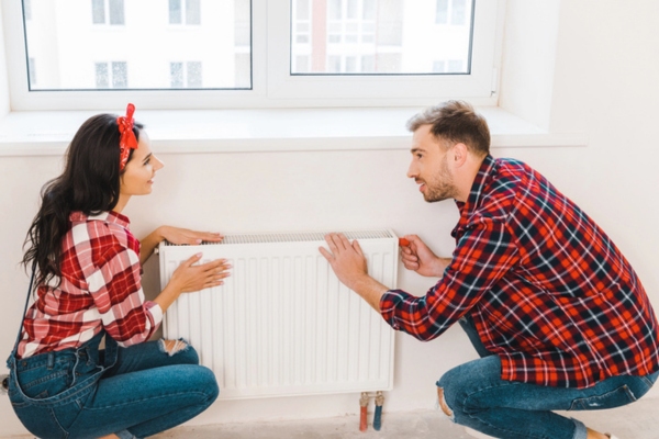 image of a couple checking home heating radiator making sure it's ready for winter