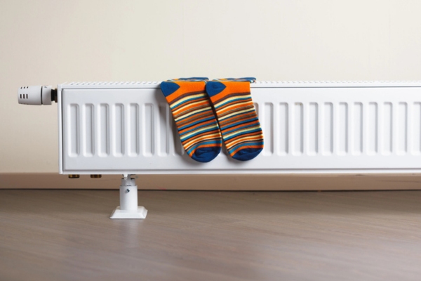 image of heating radiator in room that is powered by home heating oil with a pair of socks drying